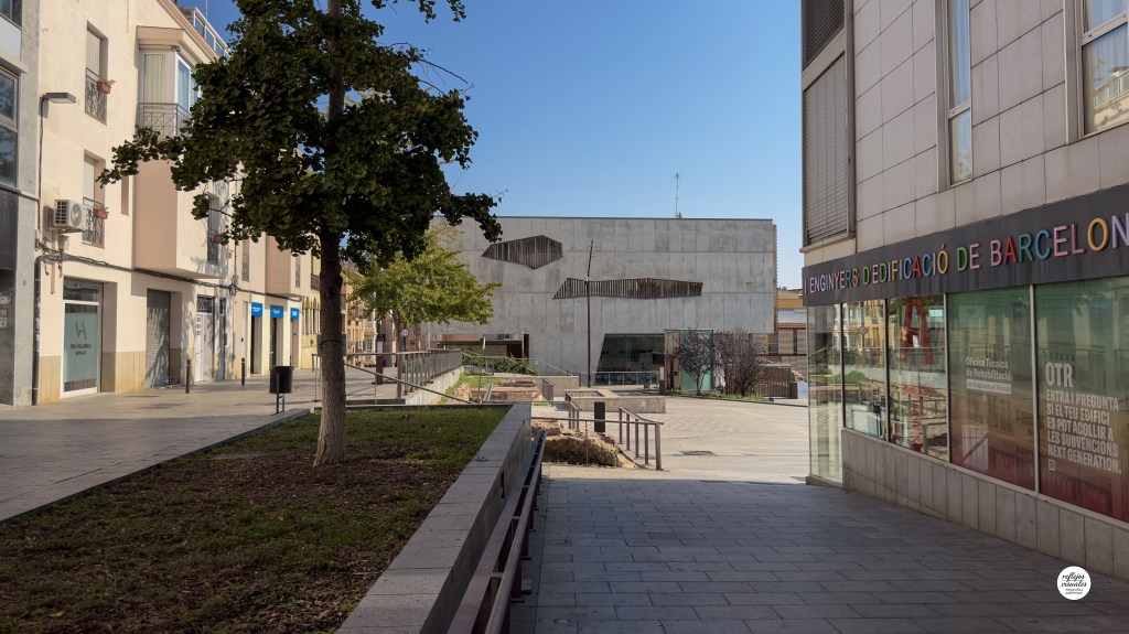 Fachada moderna de líneas rectas y hormigón con reflejos urbanos.