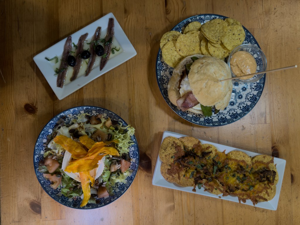 Vista cenital de una mesa con varios platos de la nueva carta del Cafè de Mar, en Mataró, mostrando una propuesta de gastronomía de proximidad en un espacio cultural.