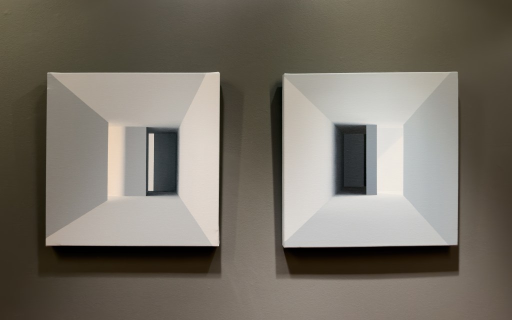 Dos obras geométricas de Monica Dixon enfrentadas en sala, con luz suave que define planos y profundidad.